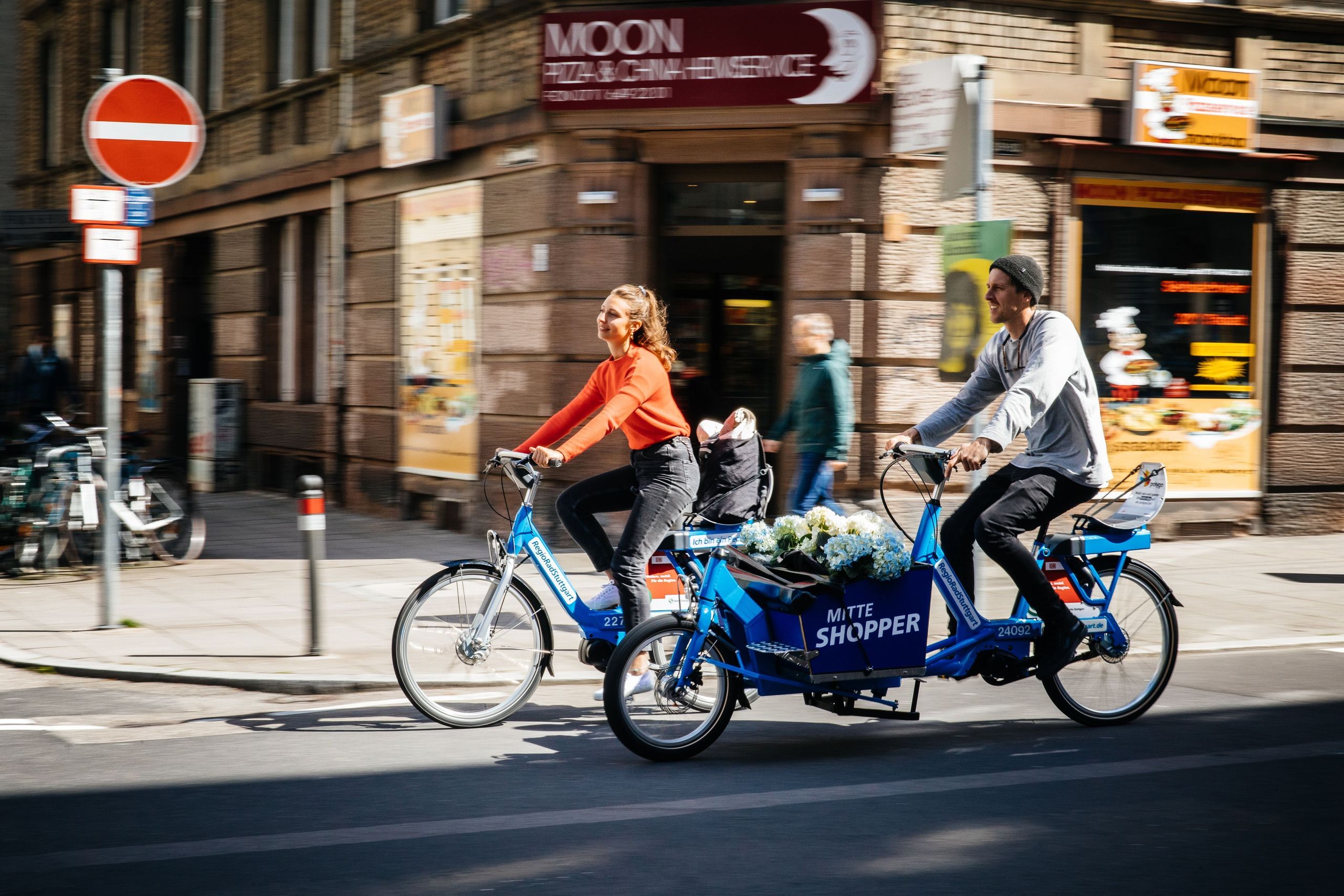 Zwei Personen fahren auf RegioRadStuttgart-Call a Bike Fahrrädern durch eine Straße in der Stadt..